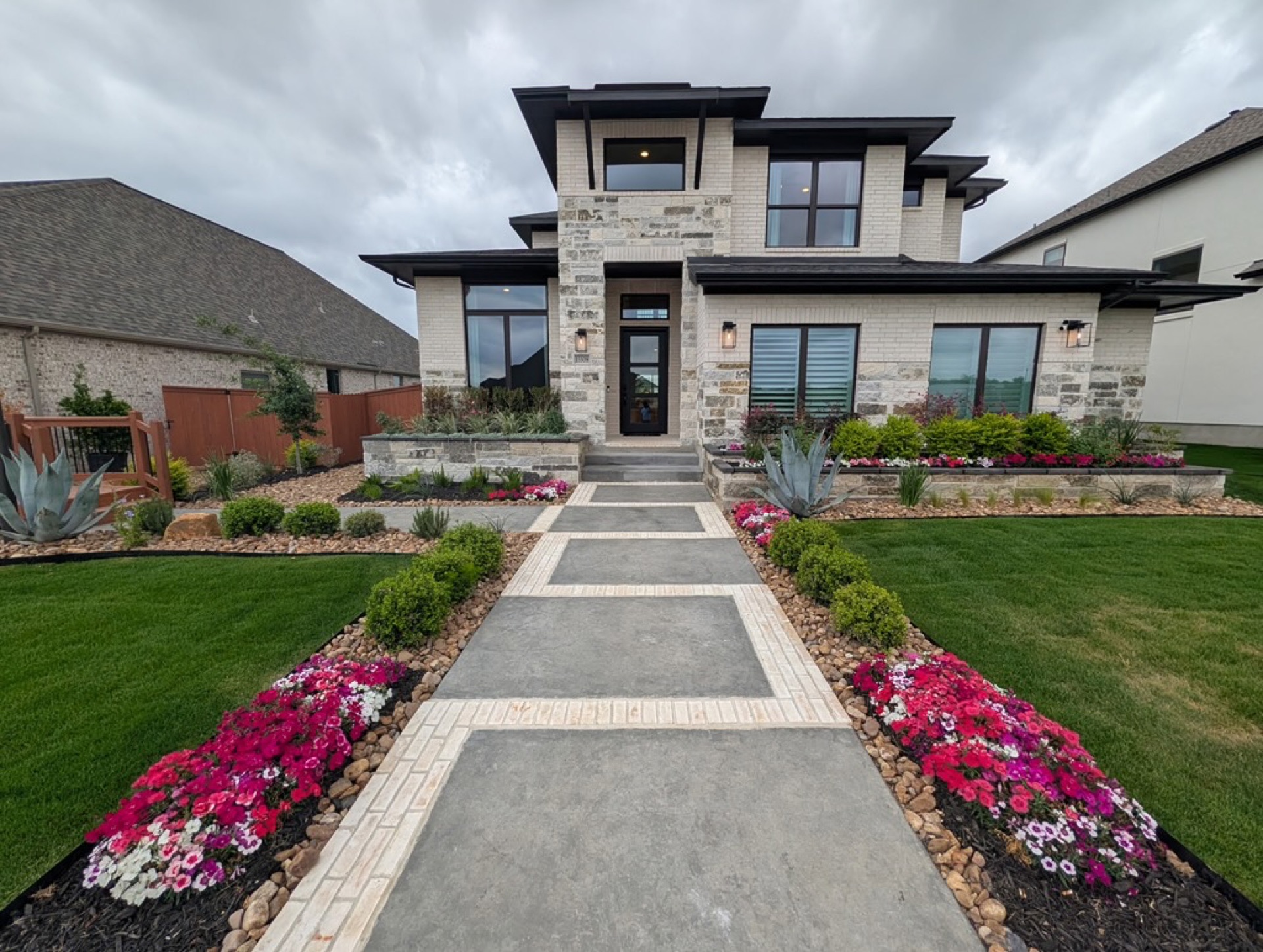 Front entry walkway lined with vibrant pink and white flower beds