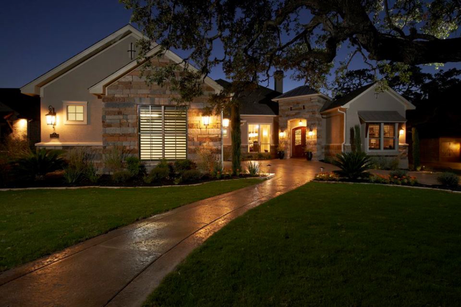 Stone home entry walkway with landscape lighting at dusk